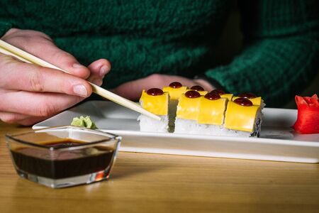 Men's hands hold sushi with chopsticksの写真素材