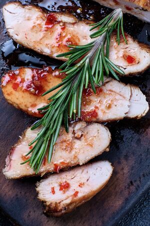 Grilled chicken fillets on wooden cutting board with sauce and rosemary. Close-upの写真素材