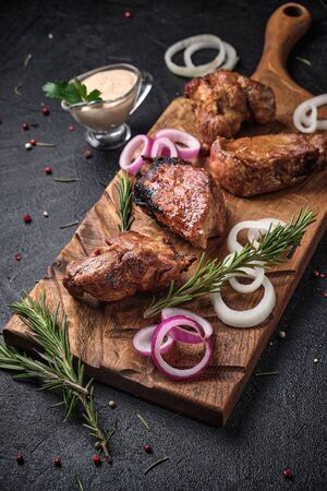 Fresh shish kebab with rosemary, onion and  white sauce on a wooden cutting board. On black backgroundの写真素材
