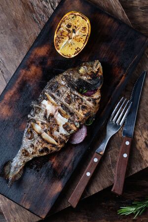 Grilled dorado served on cutting board on wood backgroundの写真素材