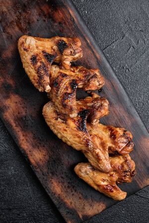 Grilled chicken wings on cutting board on dark background. Top viewの写真素材
