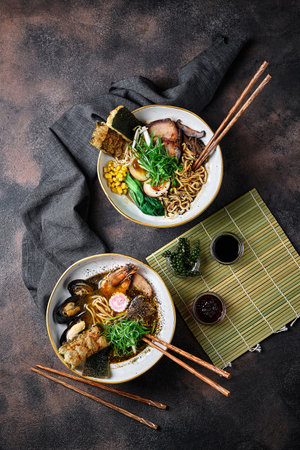 Shoyu Ramen and Udon noodles on dark table top. Japanese cuisine meat noodle soup with chashu pork and seaweeds. Asian food. Top viewの写真素材