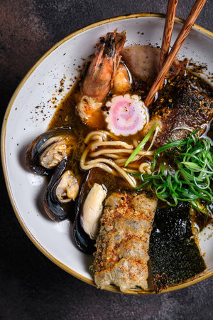 Asian style soup with udon noodles, pork, shrimp, mussel and green onions close-up in a bowl on the table. horizontal top view from aboveの写真素材