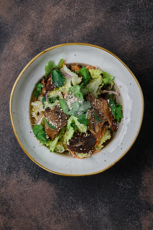 Chinese fried shiitake mushrooms, close-up in a plate on dark background. Vertical top view from aboveの写真素材