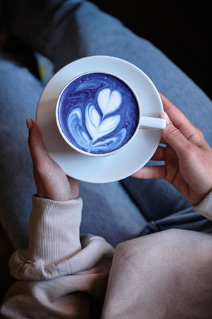 A cup of blue matcha in females hands. Top viewの写真素材