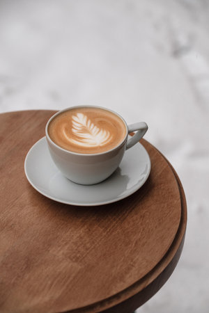 A cup of cappuccino with rose on top on wooden table. Table on the snow. Winter.の写真素材