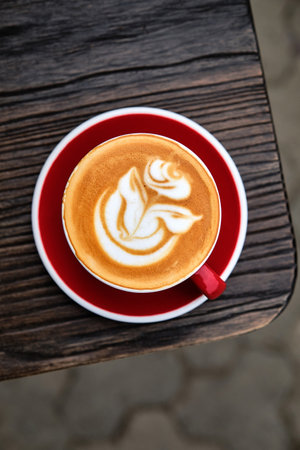 A cup of cappuccino with rose on top on wooden table. Top viewの写真素材