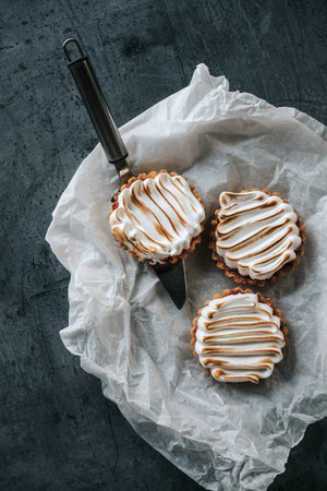 Three lemon tartalets and cake spatula on gray backgrond
