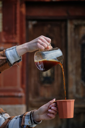 Girl pours black coffee into a cup from glass teapot.の写真素材