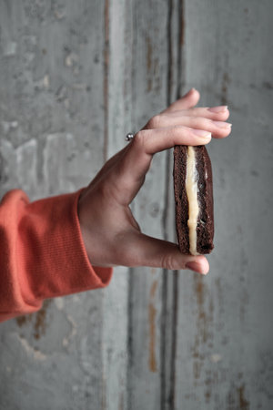 Females hand holds a whoopie pie on grey wall backgroundの写真素材