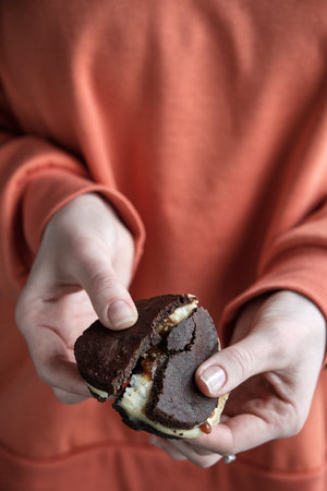 Girl in red sweater holds broken chocolate cookie. Whoopie pieの写真素材