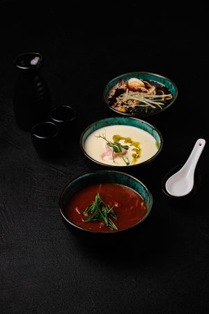 A variety of hot dishes in the restaurant, healthy food. Japanese miso, Korean Kimchi Jiggae, Cheese soup on black backgroundの写真素材