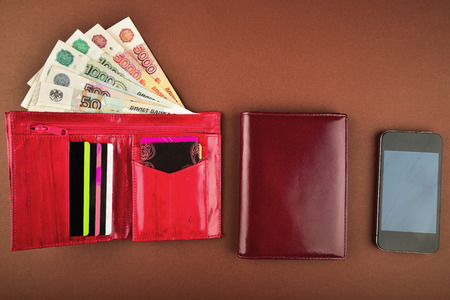 Purse,money, wallet and phone on a brown backgroundの写真素材