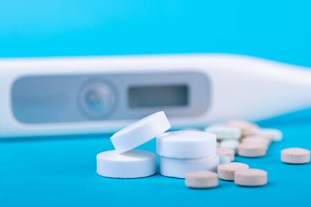 Thermometer and white tablets on a blue backgroundの写真素材