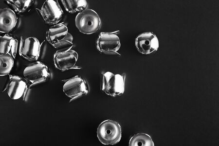 Metal jewelry accessories are scattered on a black background