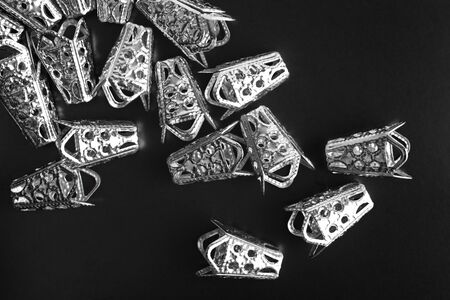 Metal jewelry accessories are scattered on a black background