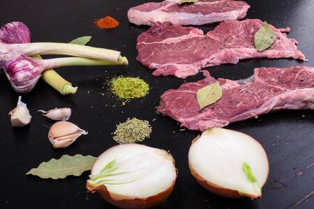 Raw, fresh meat and spices on a black wooden background.の写真素材