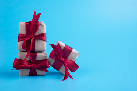 Gift boxes made of craft paper with red ribbons on a blue background.