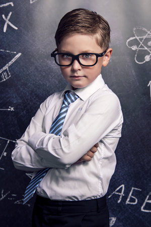 School. A boy with glasses on the background of a blackboardの写真素材