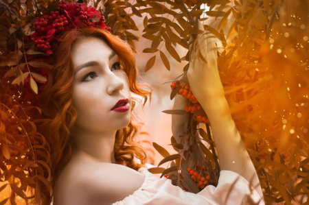 Colorful autumn portrait of beautiful red head model with rowan berriesの写真素材