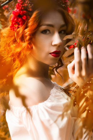 Colorful autumn portrait of beautiful red head model with rowan berriesの写真素材
