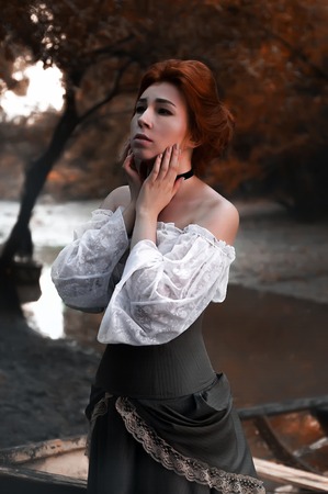 Vintage old-fashion woman near the old boat at riverの写真素材