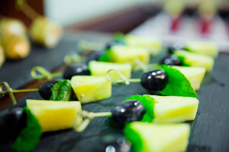 Blured cater canapes with pinapple and grapes on black tableの写真素材