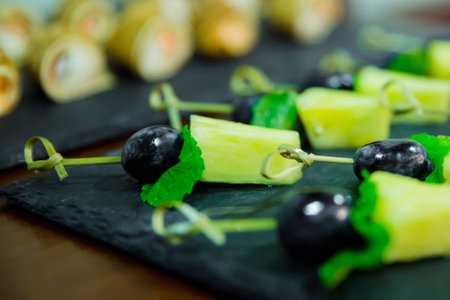 Blured cater canapes with pinapple and grapes on black tableの写真素材