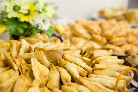Small pies lie on a plate with basket of flowers on a blue table