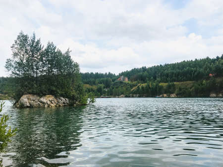 Blue lake with clear water in a mountain valley surrounded by centuries-old pine trees on a summer morningの写真素材