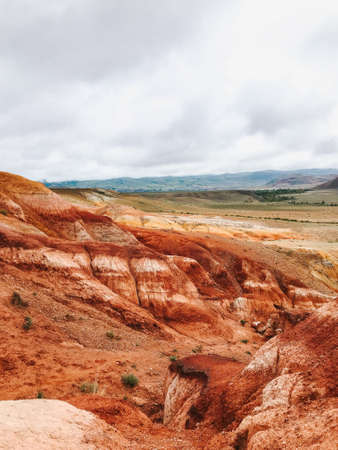 Red Martian desert multilayer mountains of clay and sand as on Mars with a cloudy sky