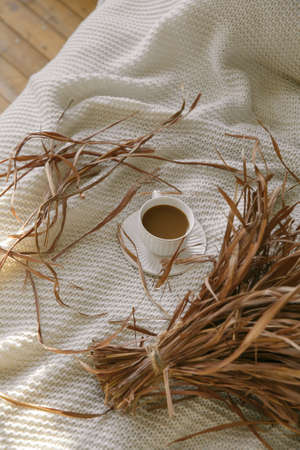 Cup of coffee in bed on a woolen blanket in the morning at sunriseの写真素材