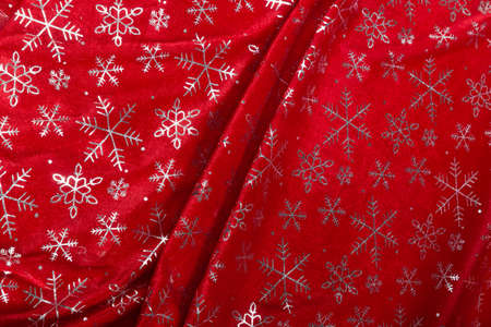 Colored red textile satin fabric folded in folds and waves with highlights and texture shimmers in...