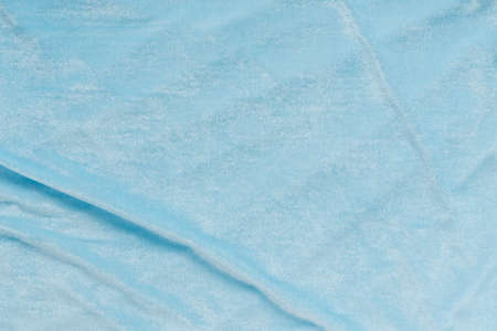 Colored blue textile satin fabric folded in folds and waves with highlights and texture shimmers in the lightの写真素材