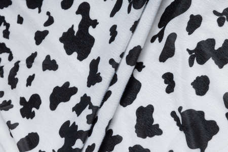 Colored black textile satin fabric folded in folds and waves with highlights and texture shimmers in...