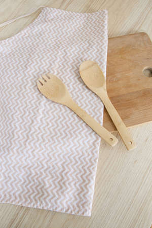A wooden spoon and fork lies on an apron in a light Scandinavian kitchen in the morningの写真素材