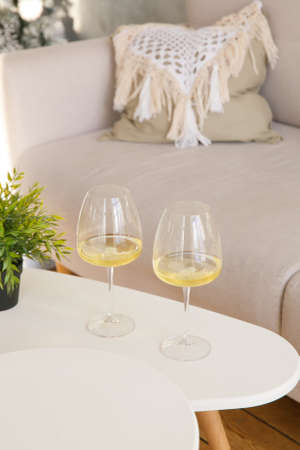 Two glasses of white wine are on the side table near the windowの写真素材