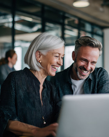 Digital nomads of different ages collaborating on a creative project in a shared workspace with natural light. Illustrates the flexibility of the gig economy.の素材