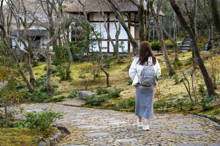 A woman with a backpack walking along a path in a Japanese gardenの写真素材