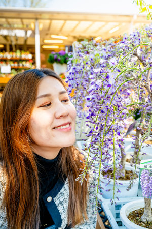 Tokyo, Japan - April 15, 2024: Girl poses with wisteria flowers in the garden.の写真素材
