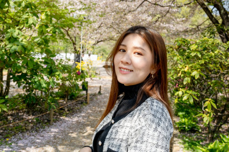 Tokyo, Japan - April 15, 2024: Sakura trees in Ashikaga Flower Park. Girl taking photo