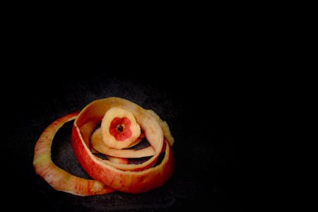 There is no skin on the apple pulp, and the remaining apple skin is a hollow apple with black backgroundの写真素材