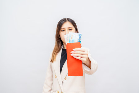 Taiwanese girl holding a red envelope with money, Lunar New Year red packet with cash, bonus and...