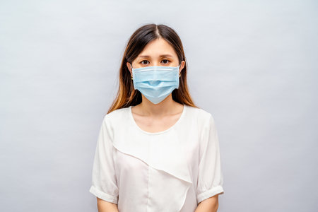 Woman Wearing a Face Mask Feeling Unwell, Showing Signs of Fever or Fatigueの写真素材