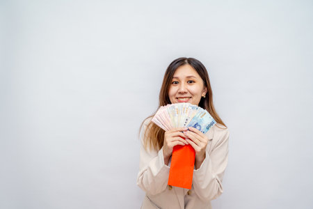 Taiwanese girl holding a red envelope with money, Lunar New Year red packet with cash, bonus and salary concept â financial success and wealthの写真素材