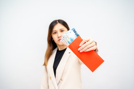 Taiwanese girl holding a red envelope with money, Lunar New Year red packet with cash, bonus and salary concept â financial success and wealthの写真素材