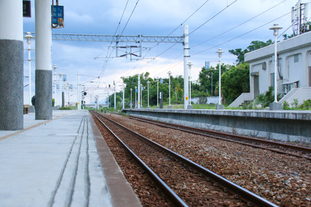 Taiwan May 21, 2024: A railway track curving into the distance beside a station platform, surrounded by greenery and power poles Fuli Station and Train in Taiwanの写真素材