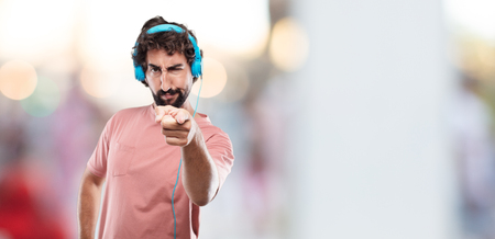 young bearded man looking angry and surprised, shouting and pointing forward, towards youの写真素材