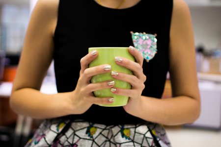 Woman hands holding a cozy green mug. Winter and Christmas time conceptの写真素材