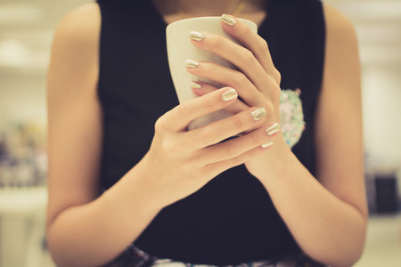 female hands holding a cup of hot coffeeの写真素材